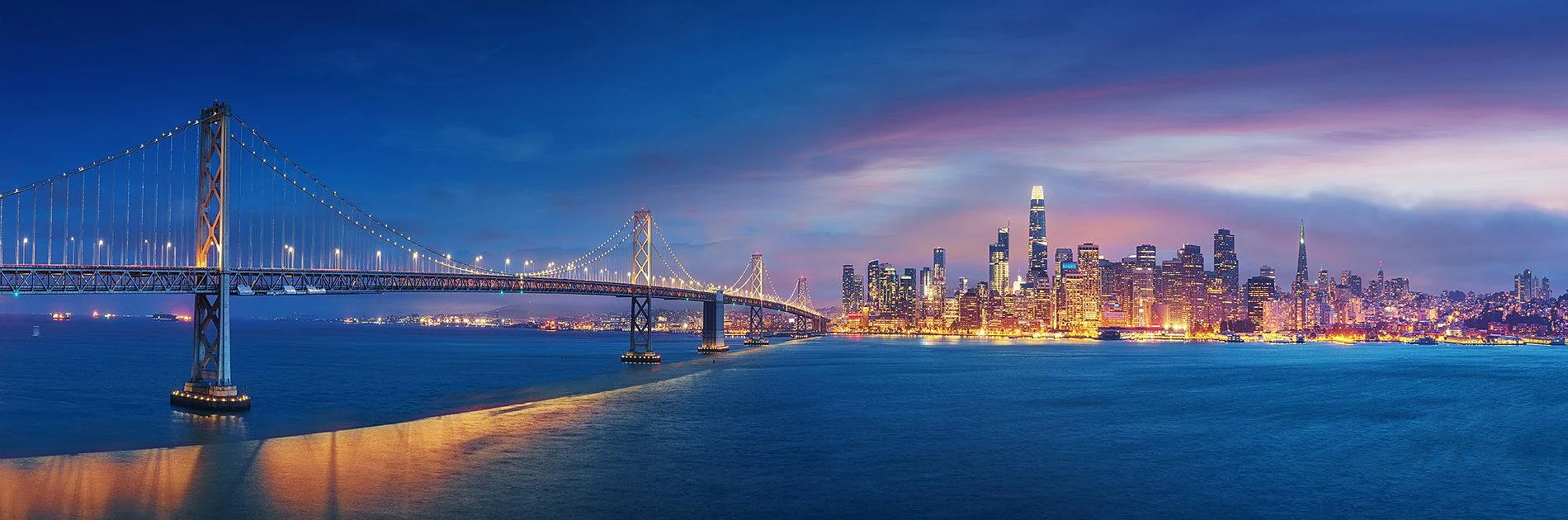 San Francisco Bay Bridge and city skyline lit up at night