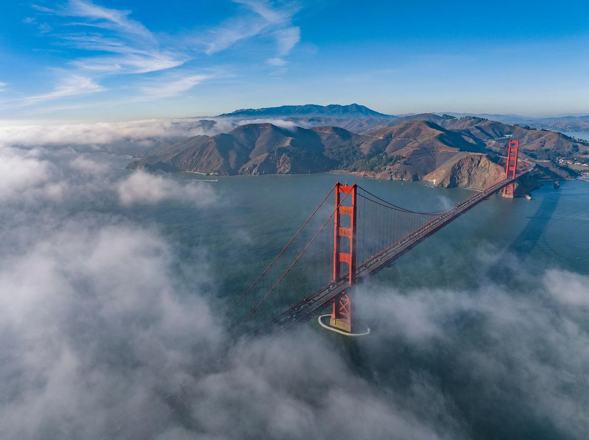 Aerial view of the Golden Gate Bridge above the fog and blue San Francisco Bay